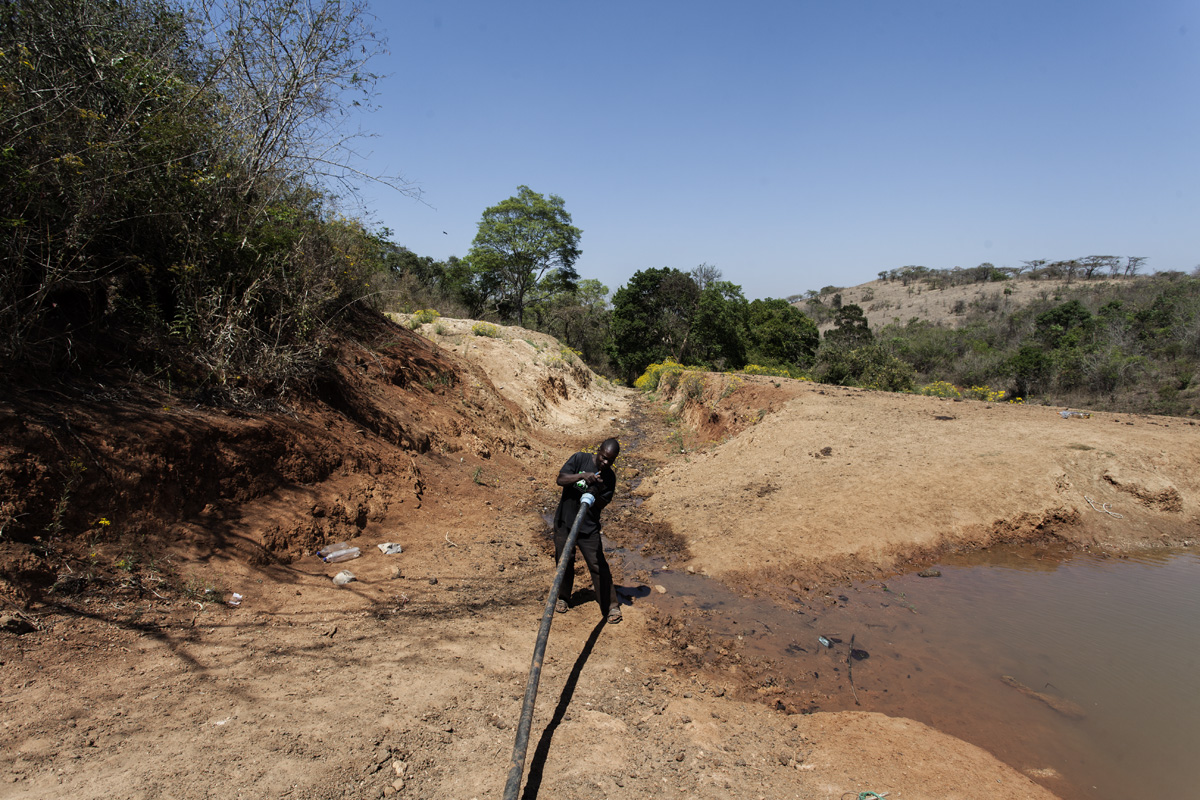 Sipho, one of the farm workers, fixes the pump at the end of the water pipe.